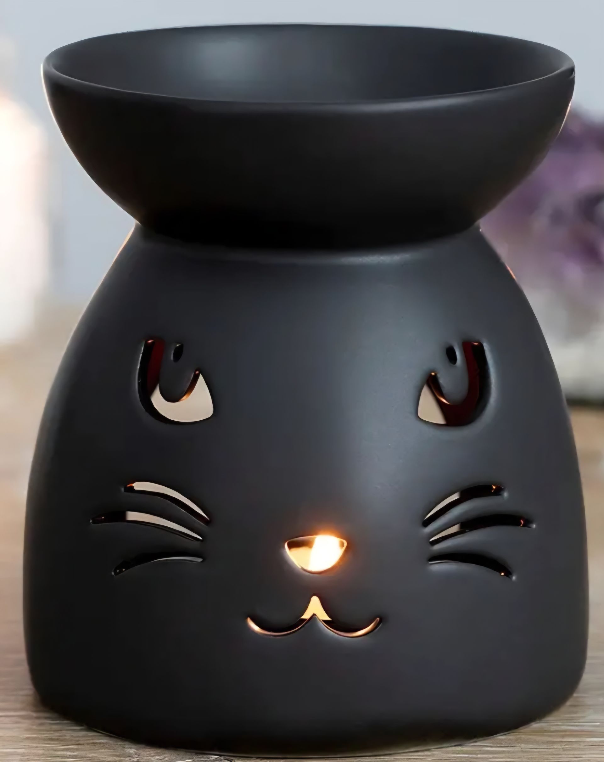Zwarte wierookbrander met een kattengezicht voor een donkere figuur met capuchon en gloeiende ogen