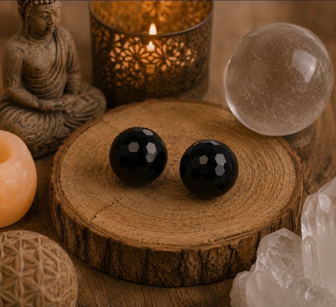 Boeddhabeeldje, zwarte stenen en kristallen bollen op een houten plank met warm kaarslicht.