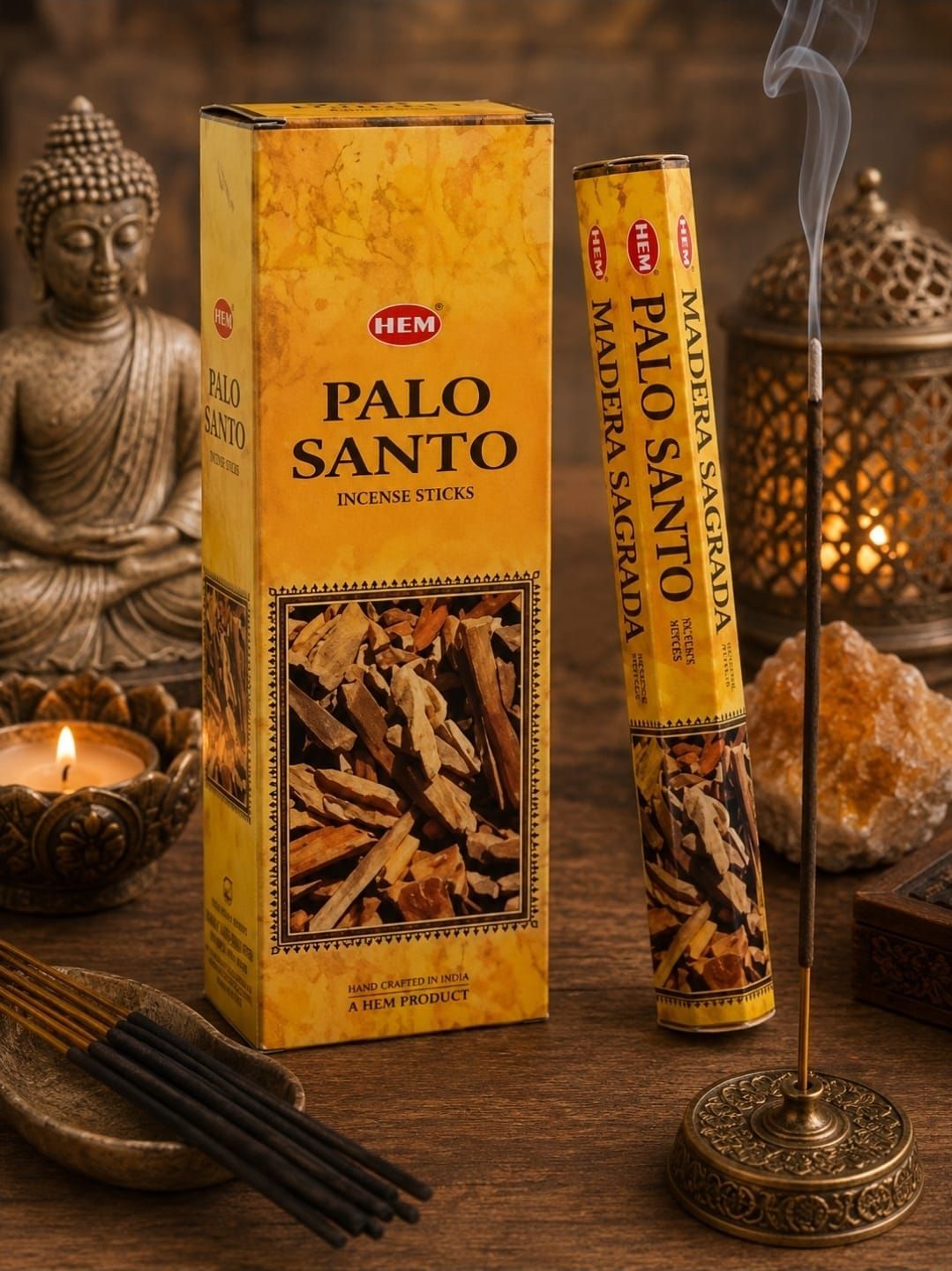 Een doosje en stokje van gele Palo Santo-wierook op een warm altaar met een Boeddhabeeld, kaars en rook.