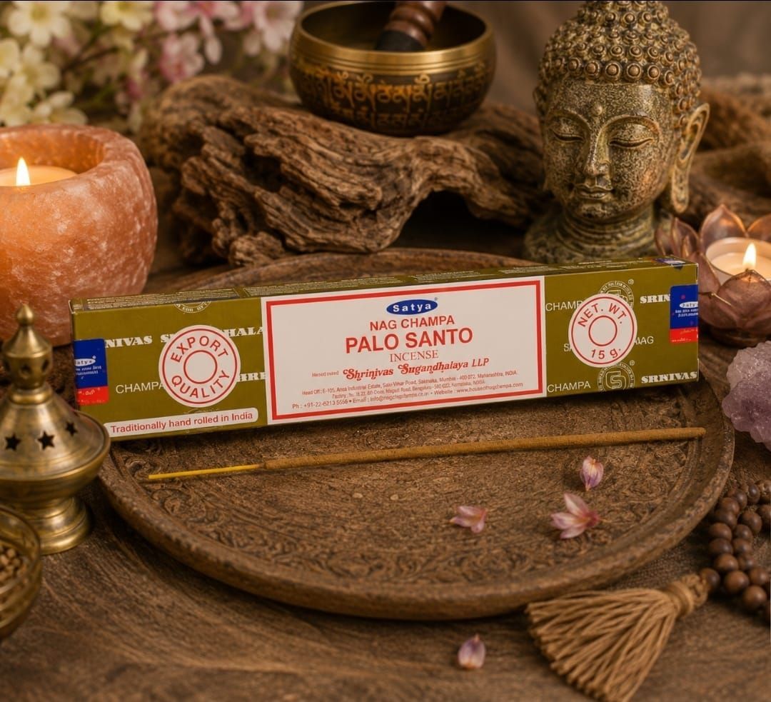 Een doosje Palo Santo-wierook op een houten dienblad met kaarsen, een Boeddha-hoofd en een klankschaal in een warme spa-omgeving.