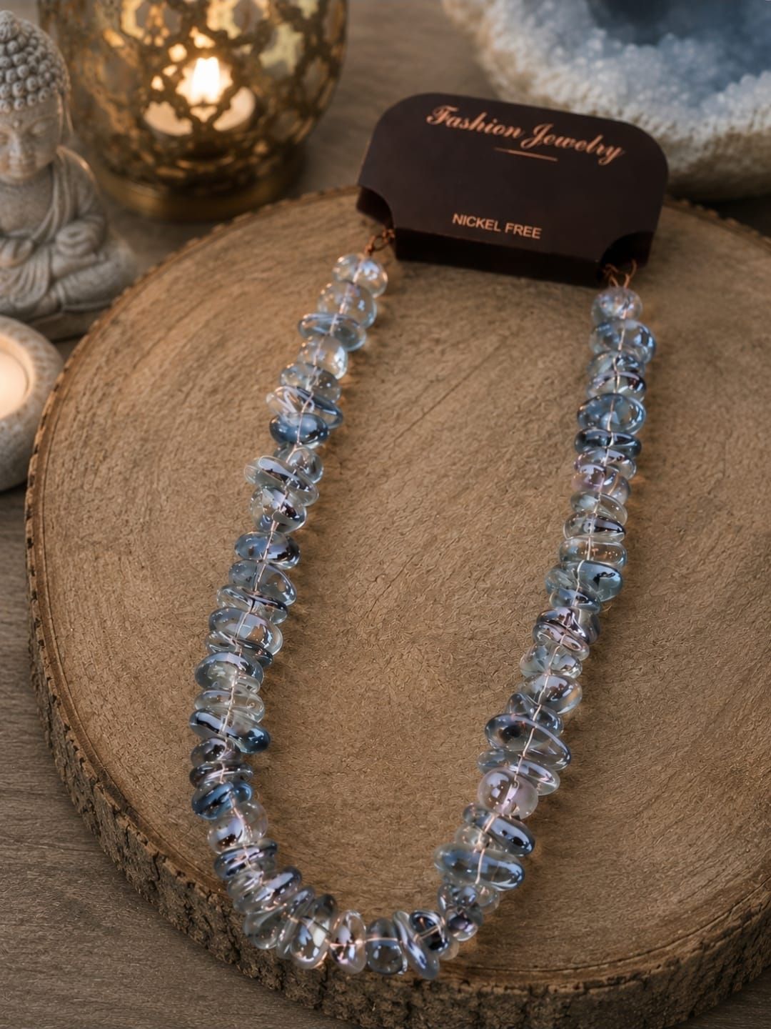 Blauwe kristallen ketting op een jute display met een zwart-goudkleurig sieradenkaartje.