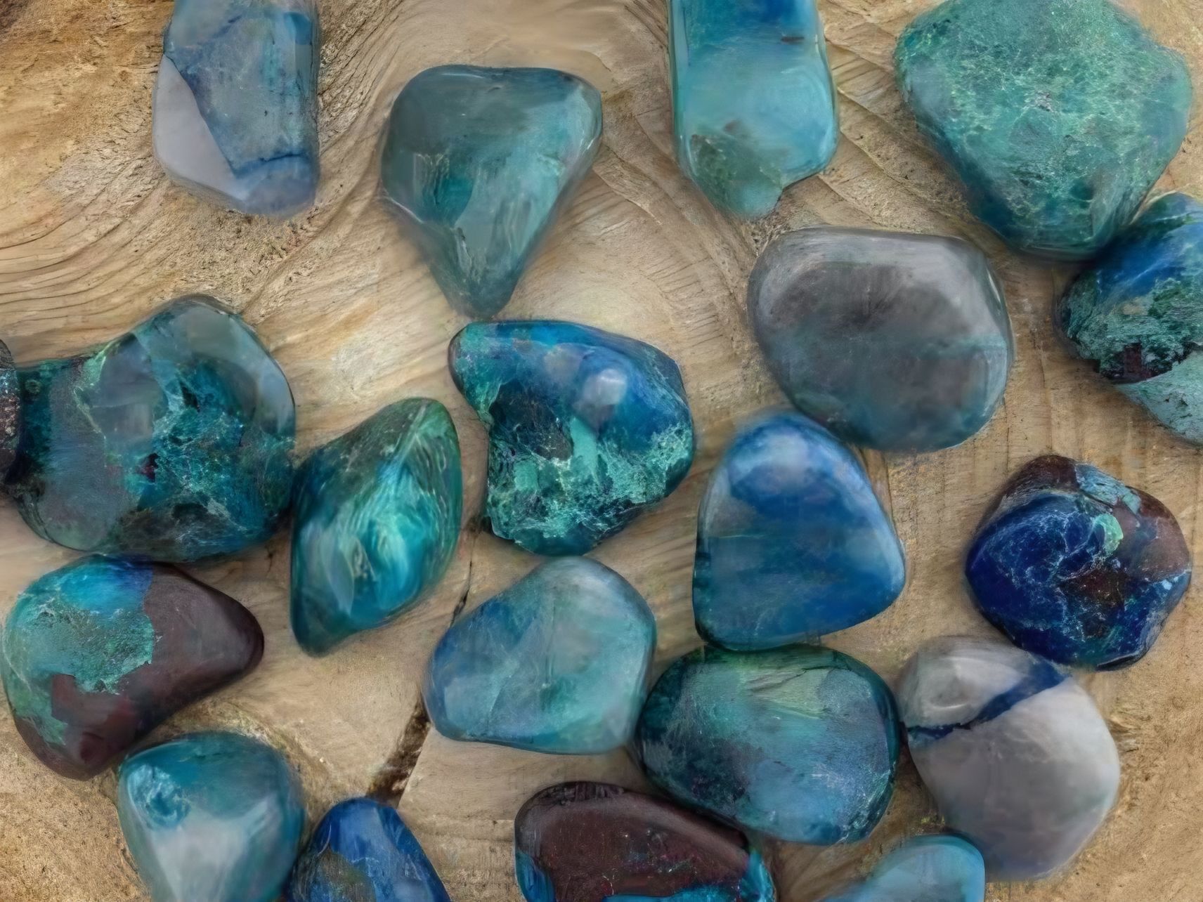 Diverse gepolijste blauwe en turquoise stenen gerangschikt op een houten ondergrond.