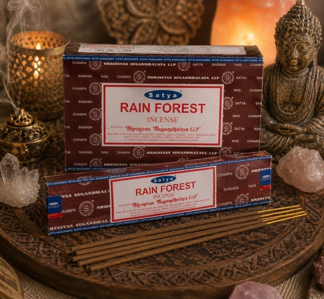 Twee doosjes Rain Forest wierook op een geweven dienblad, met een Boeddhabeeldje en een kaars in warm licht.