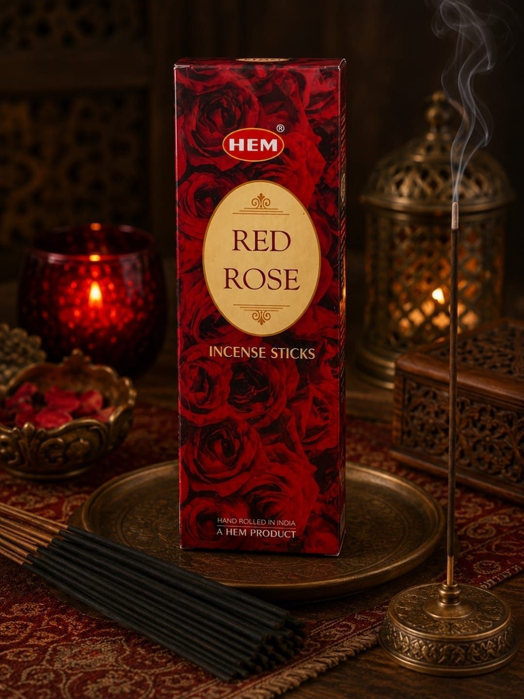 Een doosje Red Rose wierookstokjes op een dienblad, met brandende wierook en rozenblaadjes in een warme, schemerige omgeving.