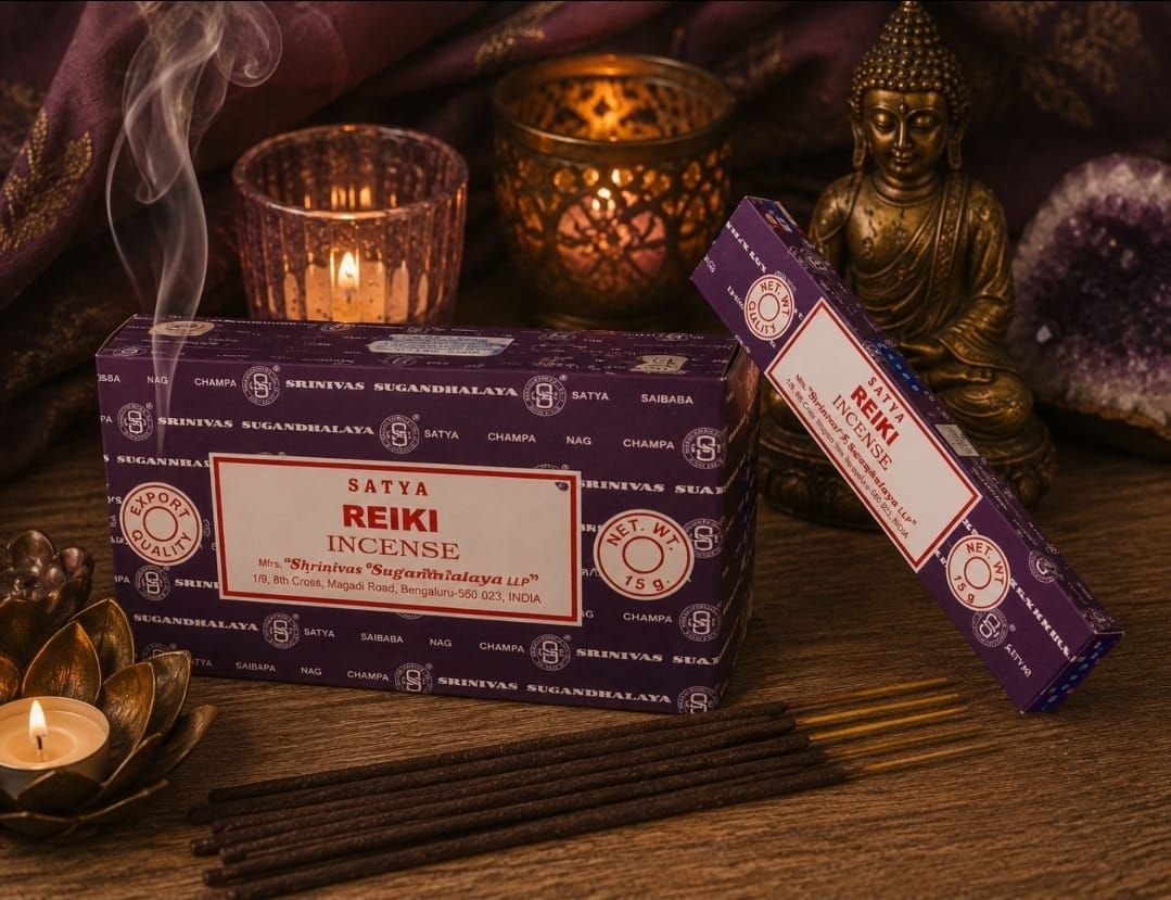 Paarse Reiki-wierookdoosjes op een houten tafel met kaarsen, een Boeddhabeeldje en kristallen.