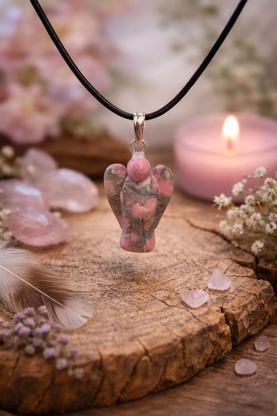 Roze bloemenhanger aan een zwart koord, bevestigd aan een rustieke houten schijf met kaarsen en bloemblaadjes.