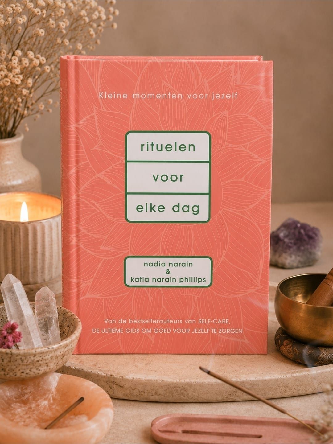 Coral book titled “rituelen voor elke dag” on a cozy tabletop with crystals and candles
