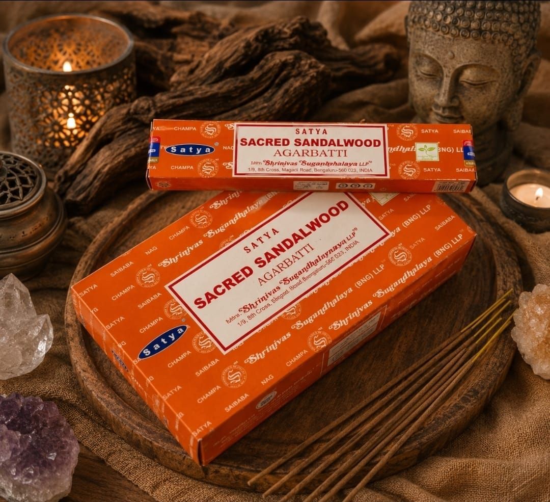 Doosjes met oranje, heilige sandelhoutwierook op een houten dienblad met Boeddhabeeldjes en warm kaarslicht.