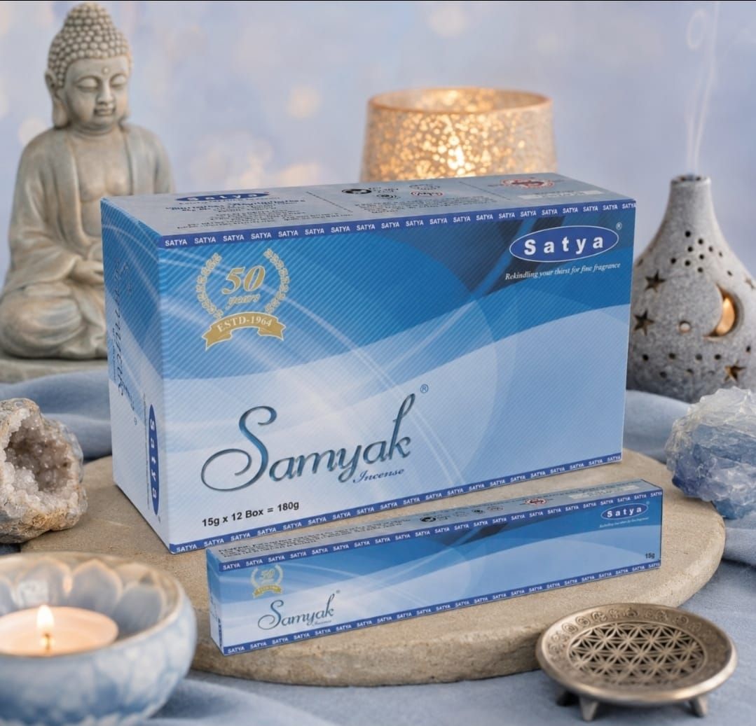 Een doos met blauwe Samyak-producten en een verpakking wierook, samen met een Boeddhabeeld en kaarsen