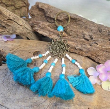 Sleutelhanger met turquoise kwastje, kralen en een goudkleurig geometrisch medaillon.
