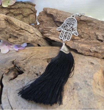 Zilveren hanger in de vorm van een hamsa met zwarte kwast.