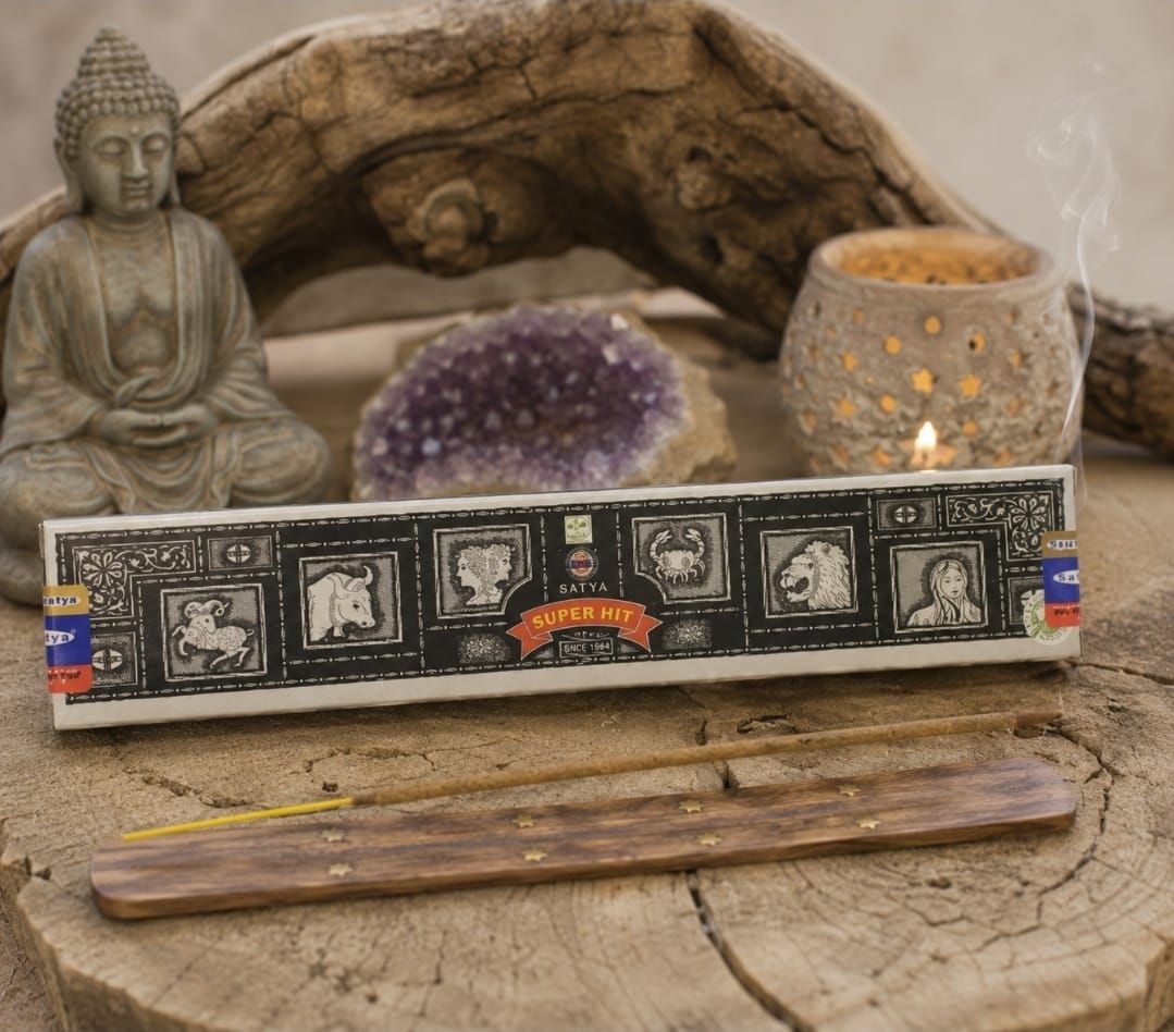 Boeddha-altaar met wierook, een kristallen cluster, kaarsen en een decoratieve wierookdoos op een houten plank.