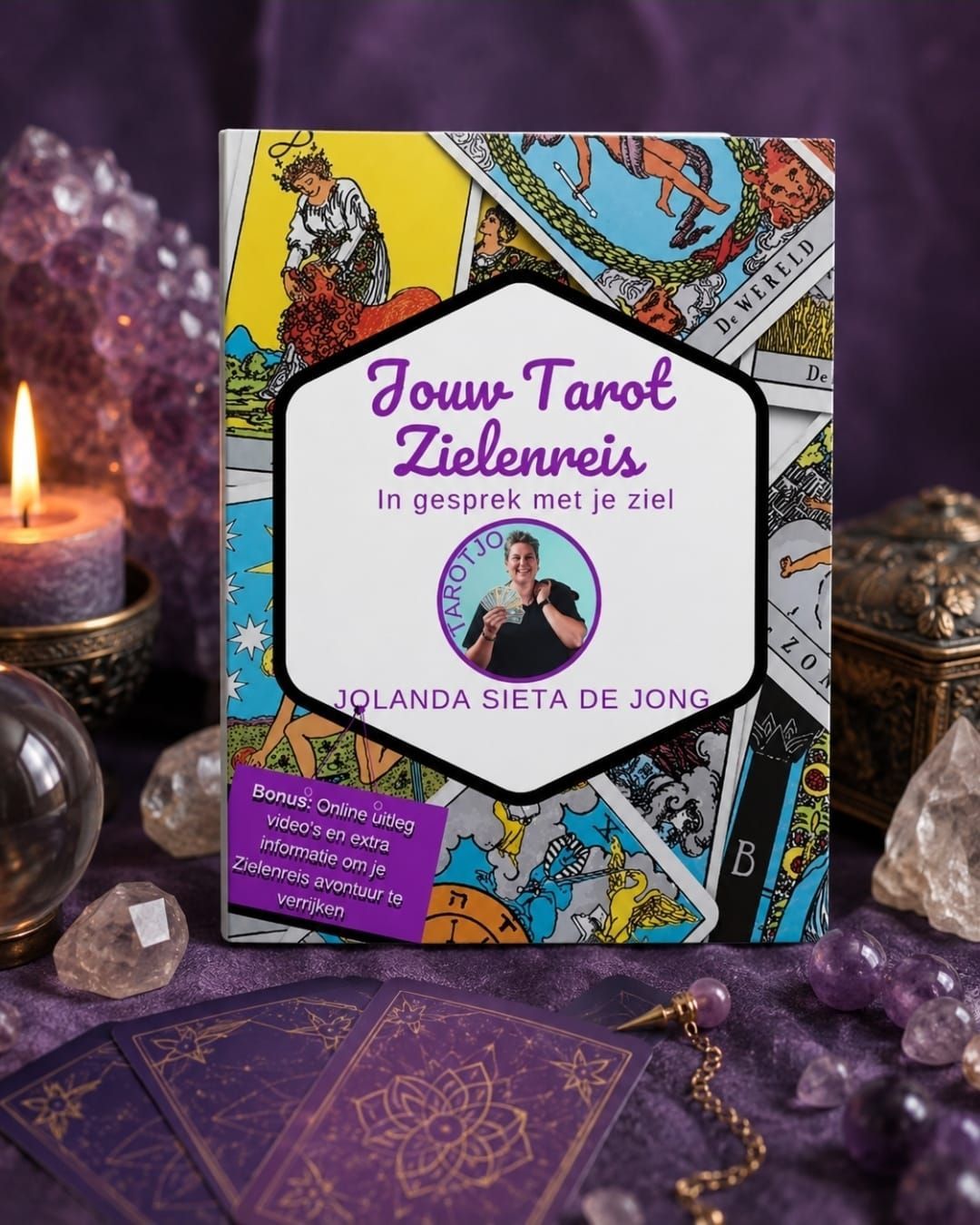 Tarotboek met kleurrijke kaft op paarse kristallen naast een brandende kaars.