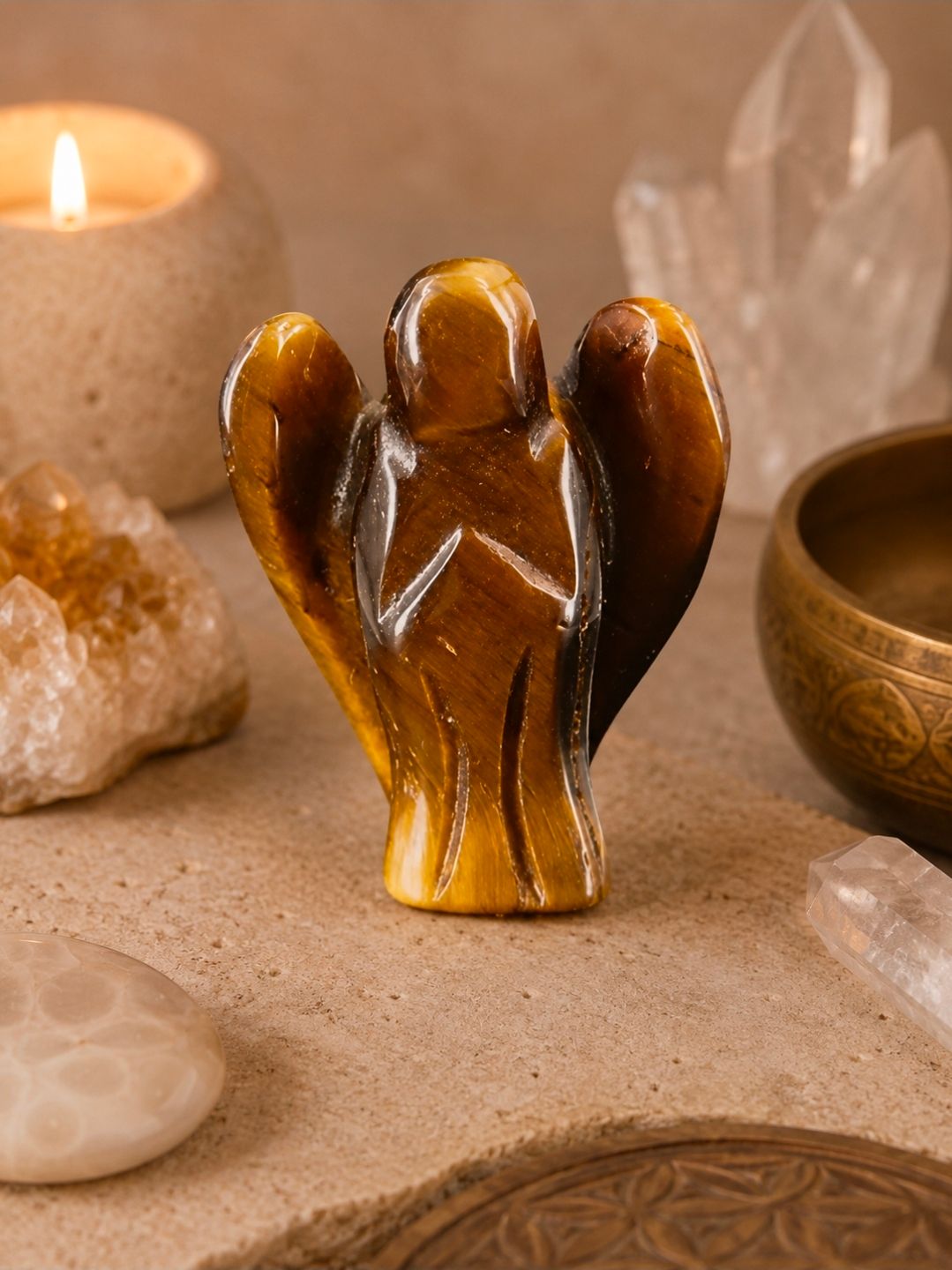 Klein amberkleurig engeltje op een stenen schaal met kaarsen en kristallen in een warme, spa-achtige omgeving.