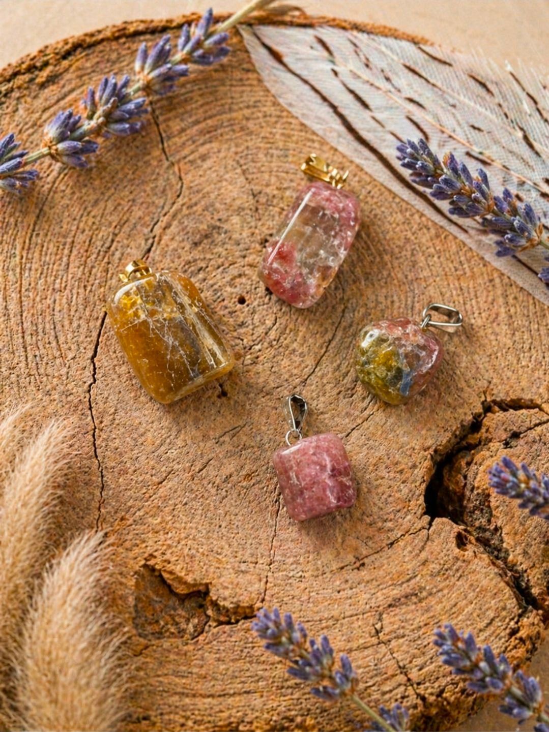 Diverse pastelkleurige glazen parfumflesjes gerangschikt op een beige, gestructureerde stof met lavendeltakjes.
