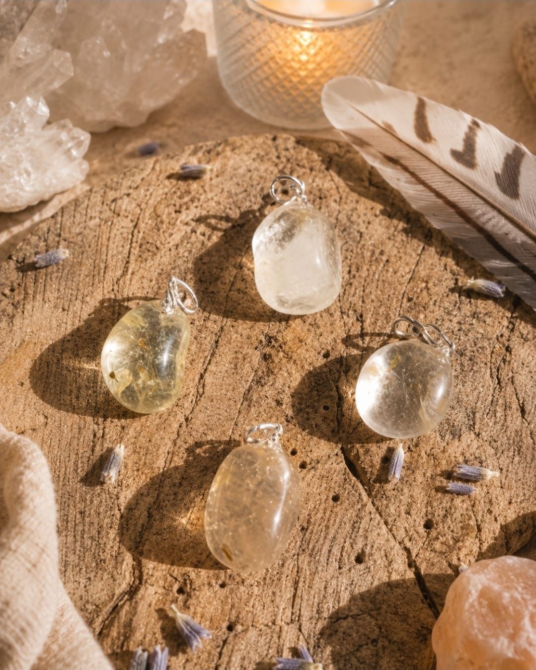Heldere kristallen en veren gerangschikt op zand rond een kaars en kwartsstenen.