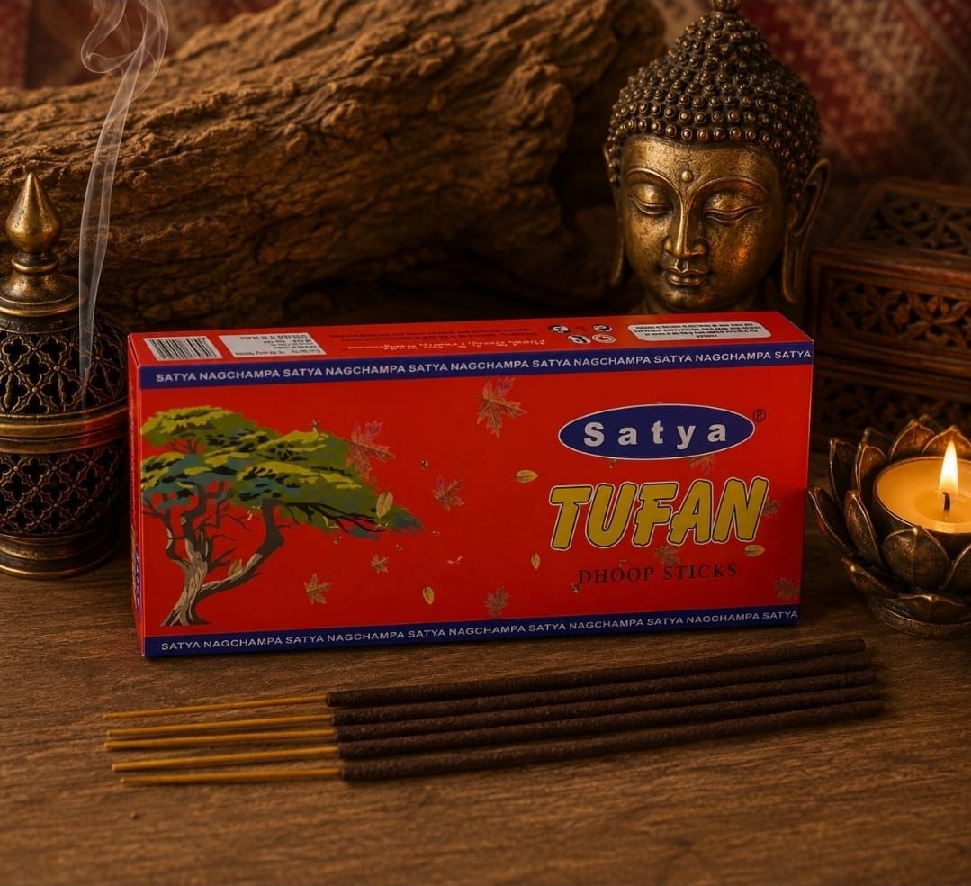 Een doosje rode Satya Tulsi wierook op een houten tafel met Boeddha-decoratie, kaarsen en wierookstokjes.