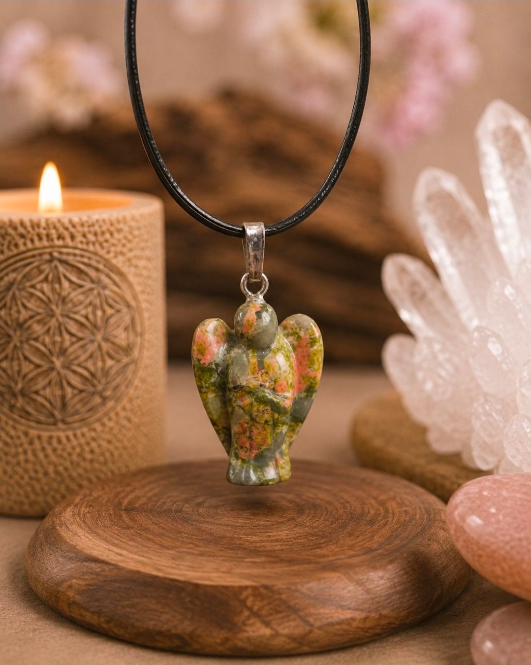 Hangerketting met een groene kristallen olifant als bedeltje op een houten standaard, naast een kaars en kwartskristallen.