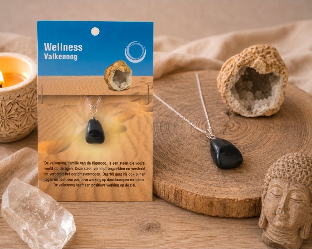 Een wellness-kettingdoosje naast een kristal, een kaars en een houten dienblad met een stenen Boeddha in een warme spa-omgeving.