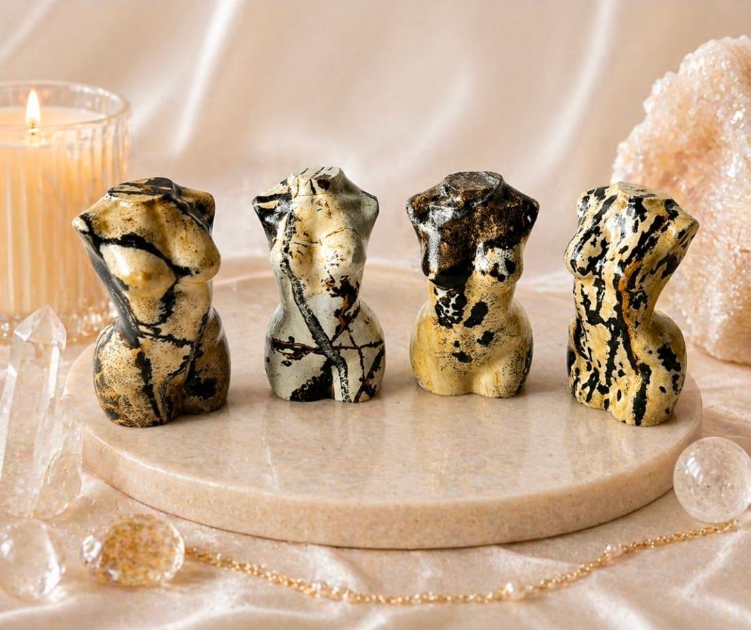 Vier gemarmerde zwart-gouden dierenbeeldjes op een rond beige dienblad met kristallen en parels.
