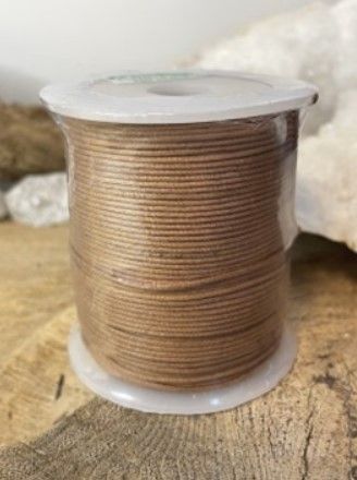 Een klosje bruin garen op een witte plastic spoel, rustend op een houten ondergrond.