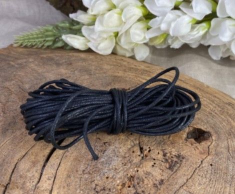 Een opgerold donkerblauw touw, samengebonden tot een bundel, met één los uiteinde dat eruit steekt.