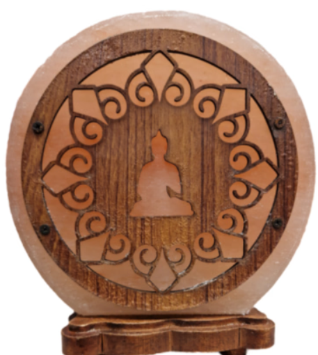 Een stralend Boeddha-silhouet in een ronde, uit hout gesneden lamp met warm oranje licht, tentoongesteld op een plank.