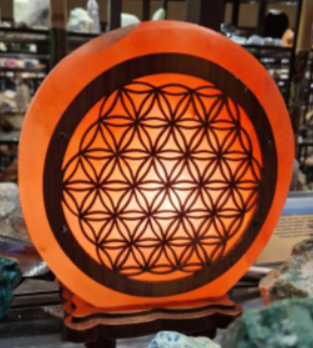 Oranje, gloeiende decoratieve lamp met een zwart heilig geometrisch patroon op een winkelplank.