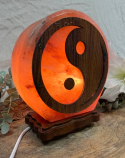 Een stralende yin-yang lamp op een houten voet, met oranje en donkerbruine accenten.