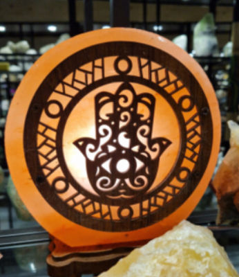 Houten Hamsa wanddecoratie met ingewikkelde zwarte uitsparingen, tentoongesteld op een glazen plank.