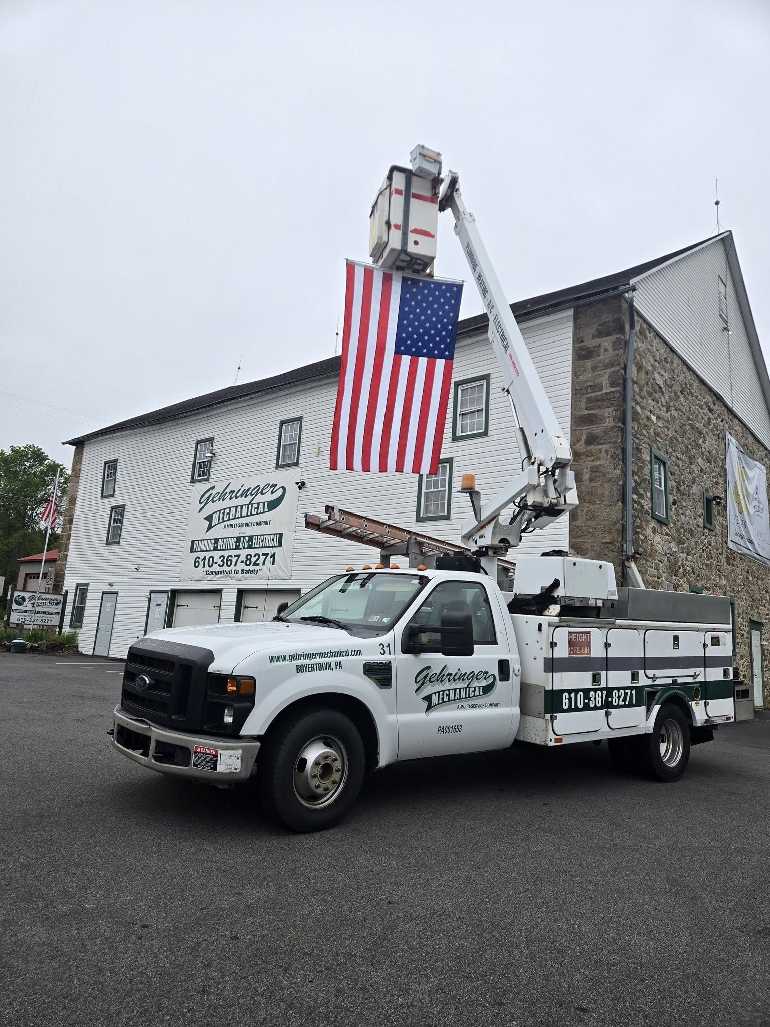 Utility bucket truck with American flag parked outside a stone church on a rainy day.
