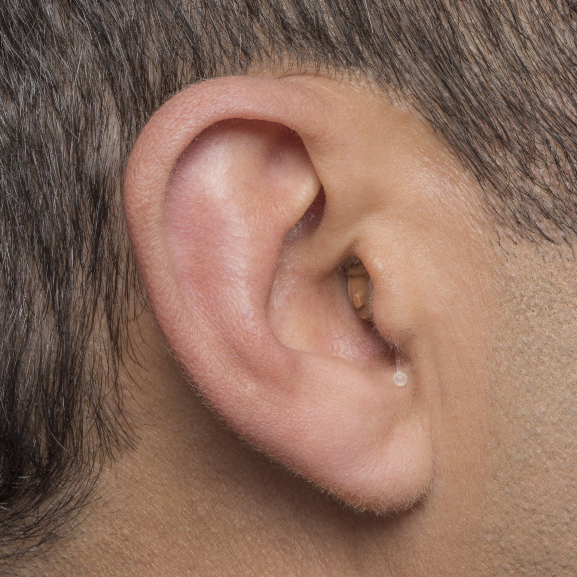 A close up of a man 's ear with a hearing aid in it