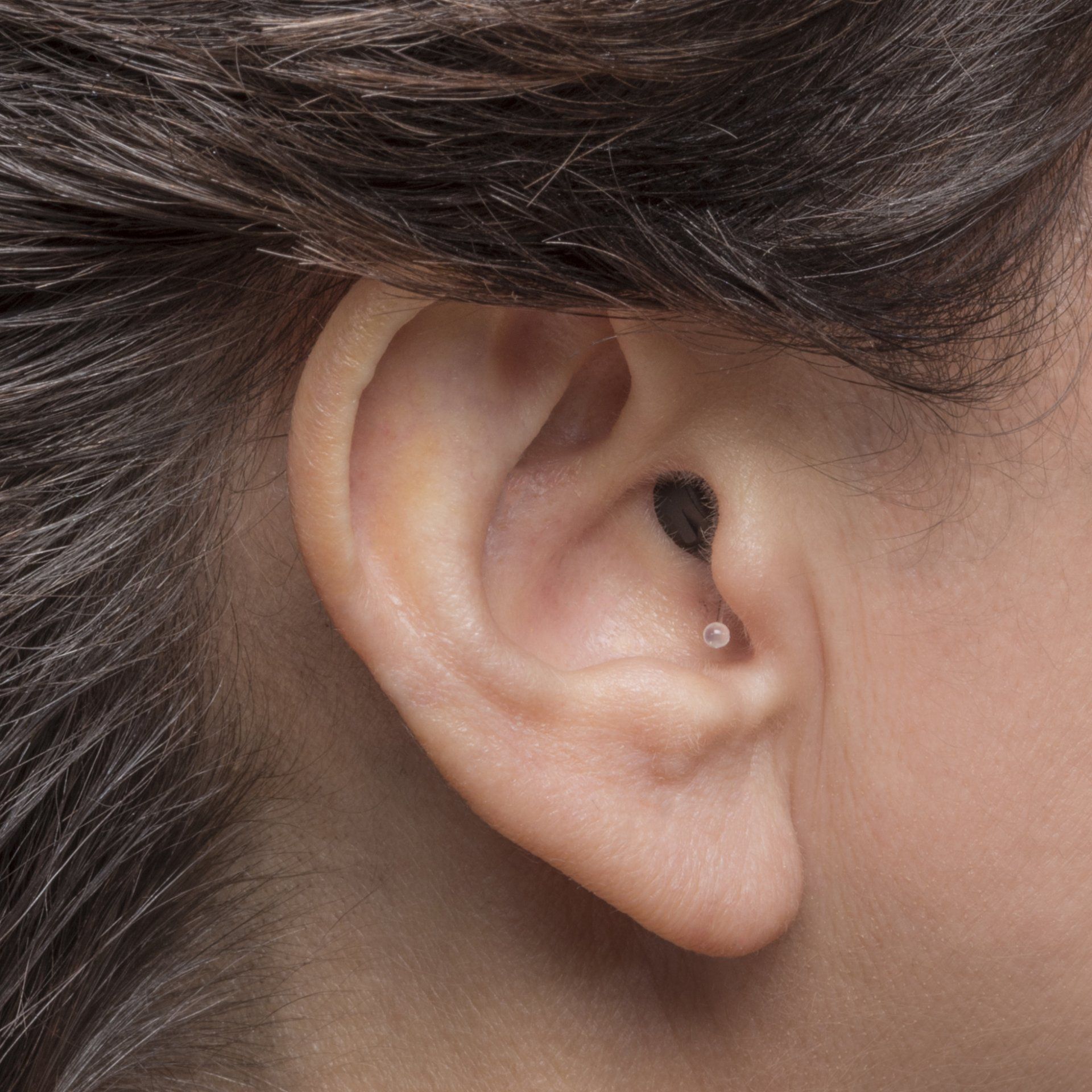 A close up of a woman 's ear with a black earring in it