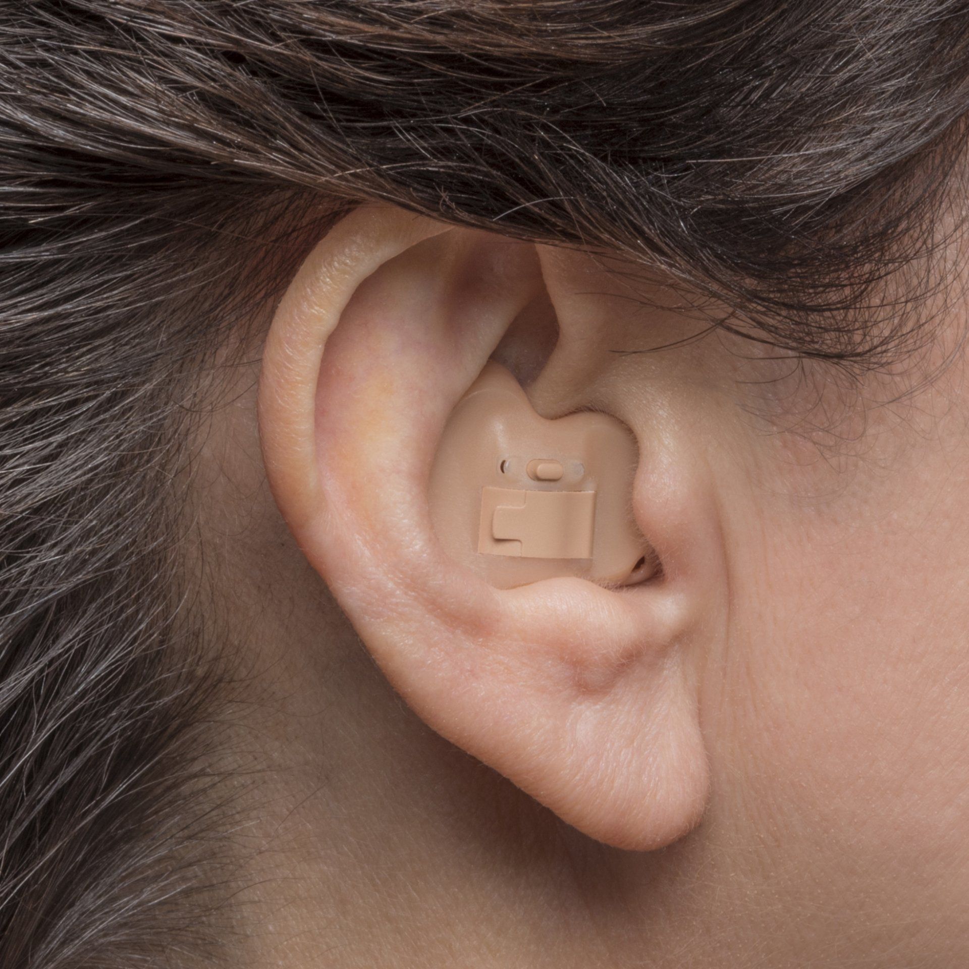 A close up of a woman 's ear with a hearing aid in it