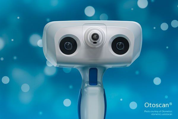 White and blue Otoscan device on a blue background with bokeh.