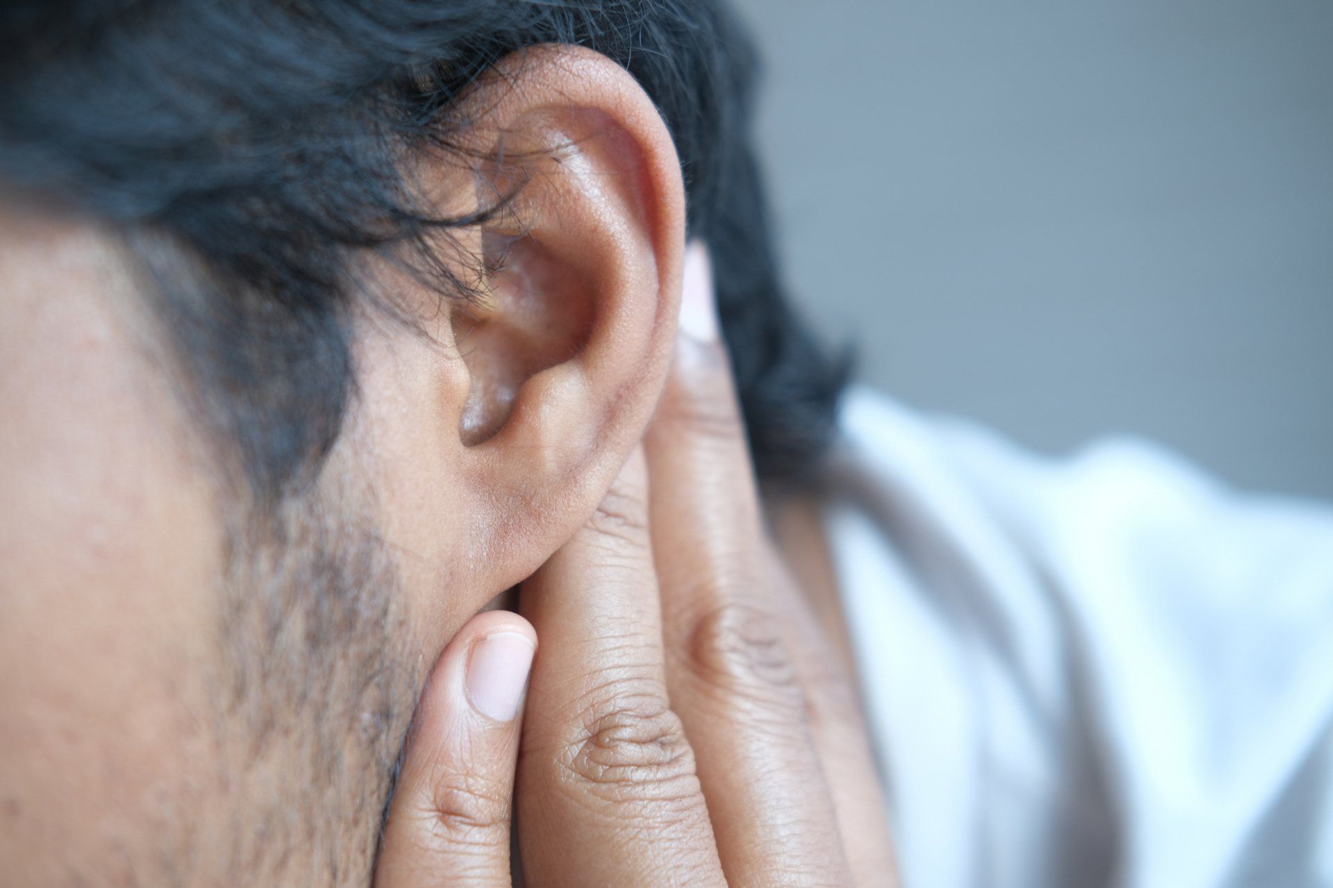 A man is covering his ear with his hands.