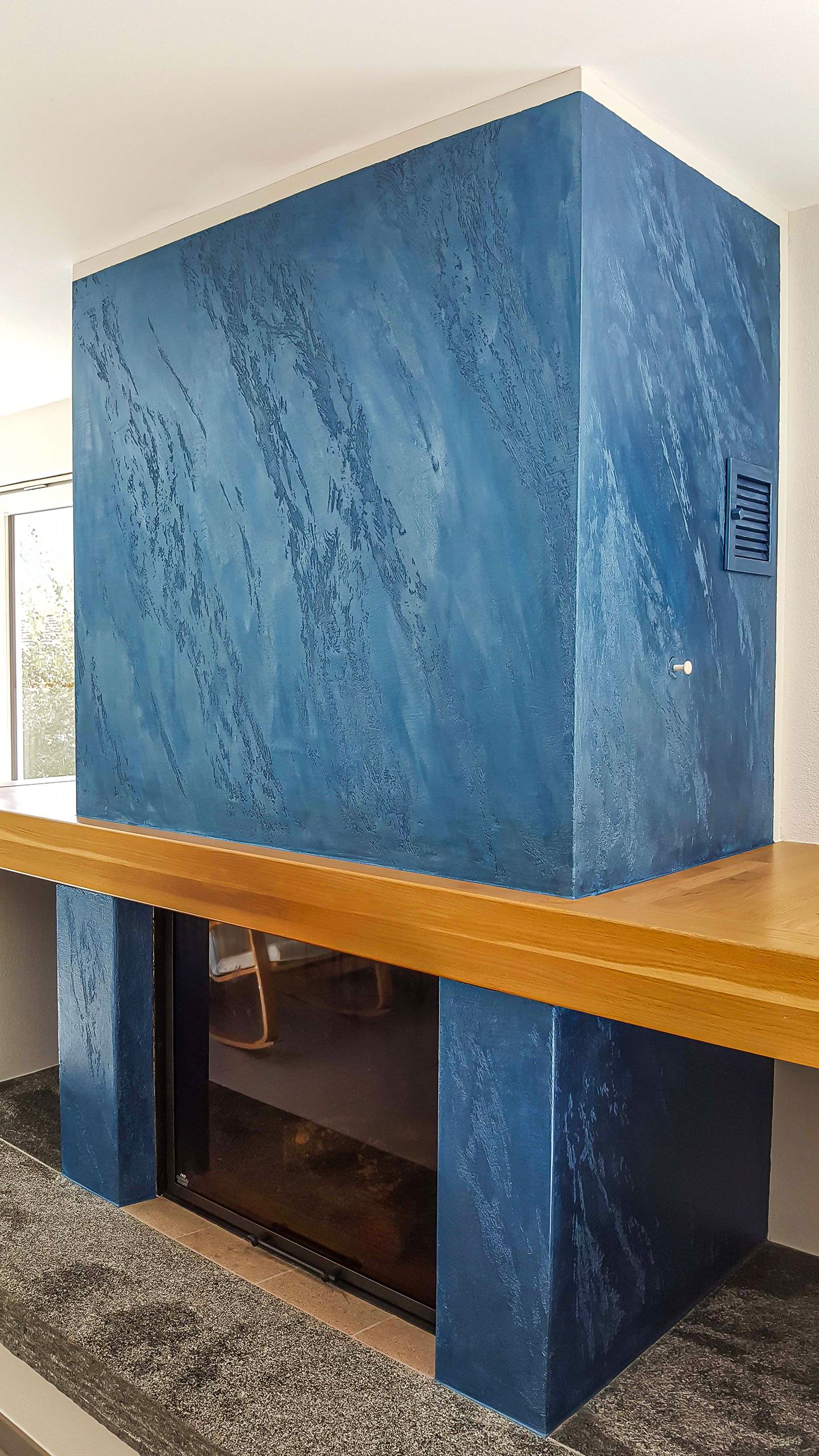 Un camino blu con mensola in legno in un soggiorno.