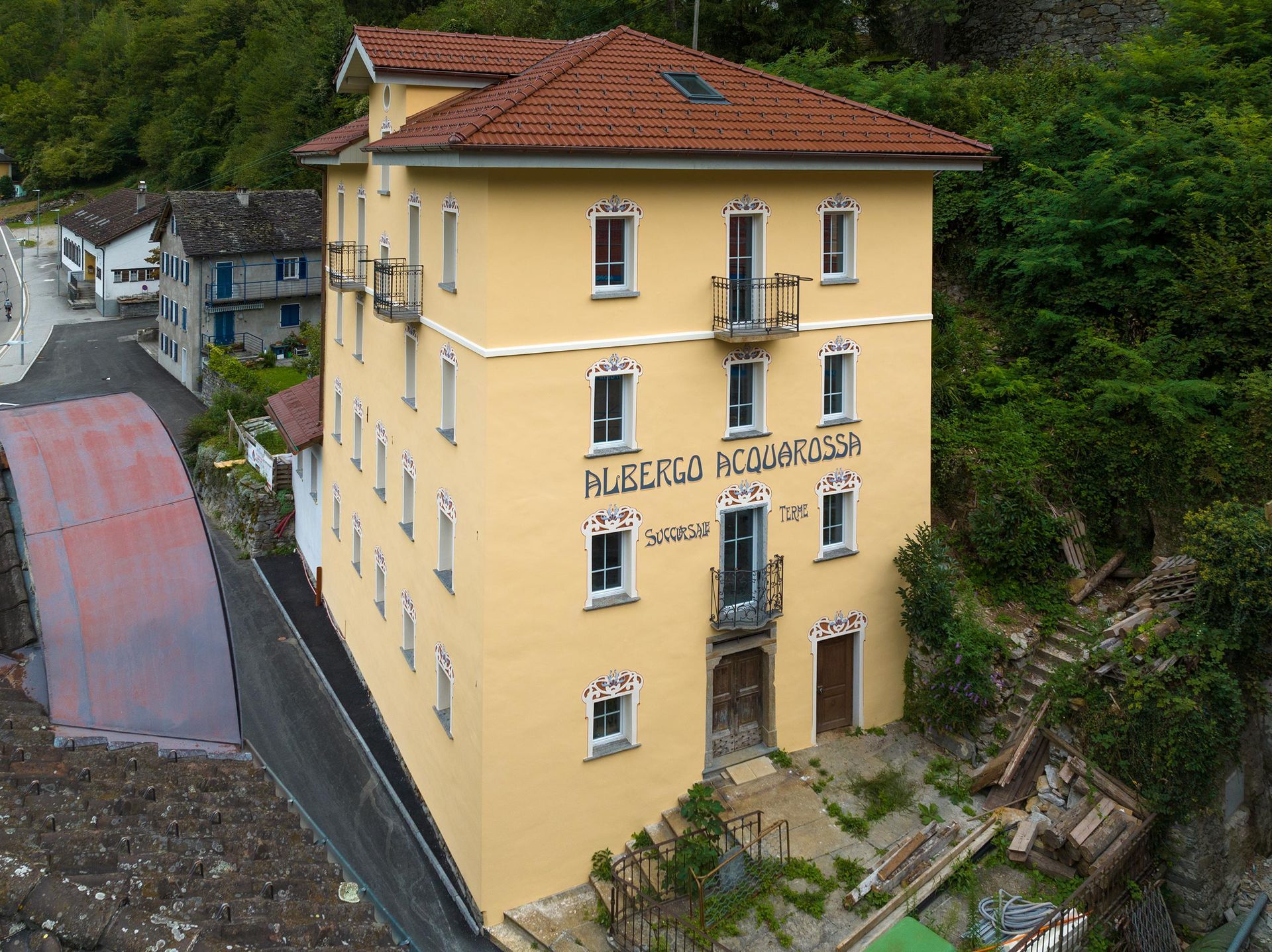 Una veduta aerea di un edificio giallo con un tetto di tegole rosse