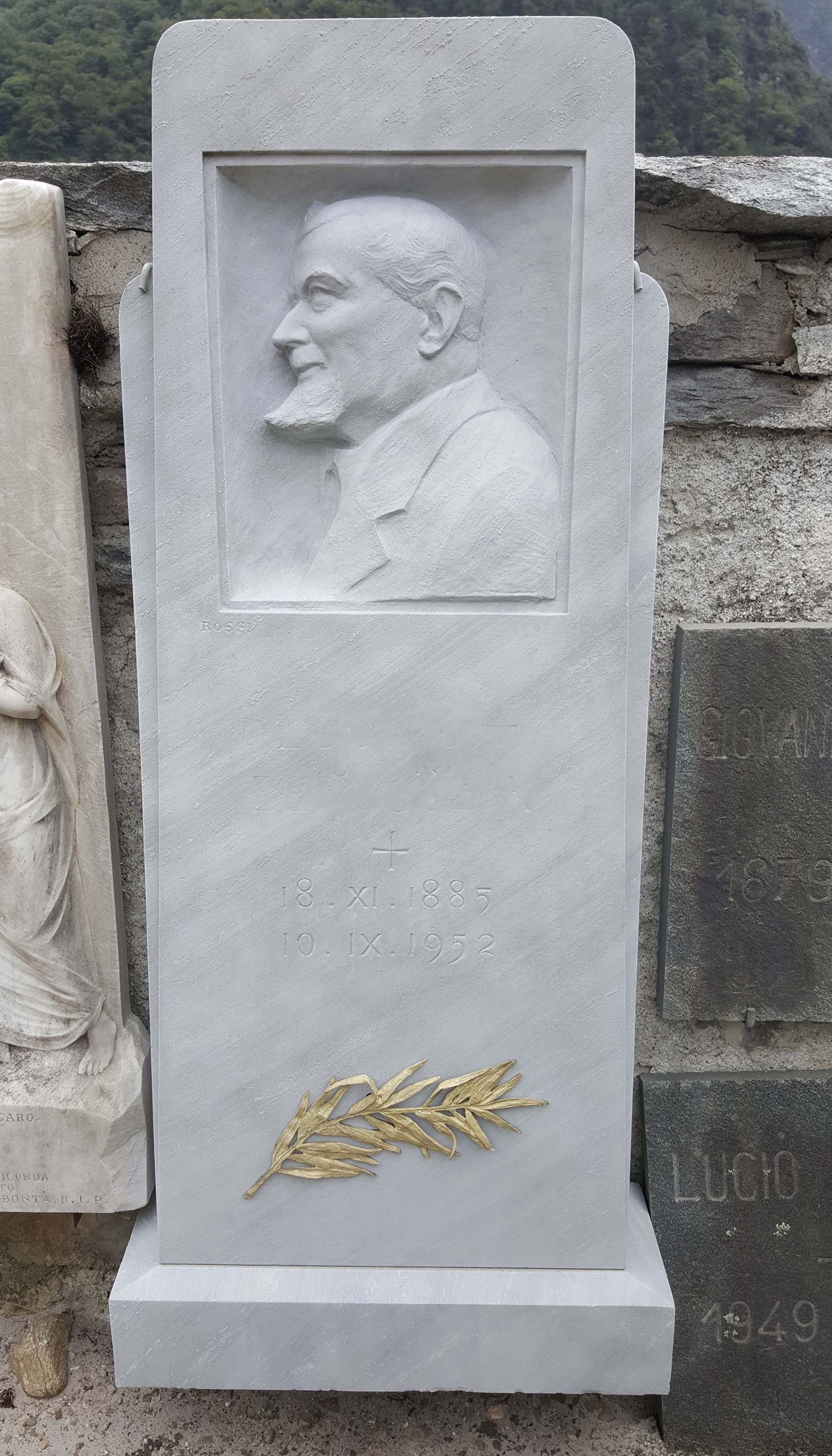 Una lapide con sopra la statua di un uomo con la barba.