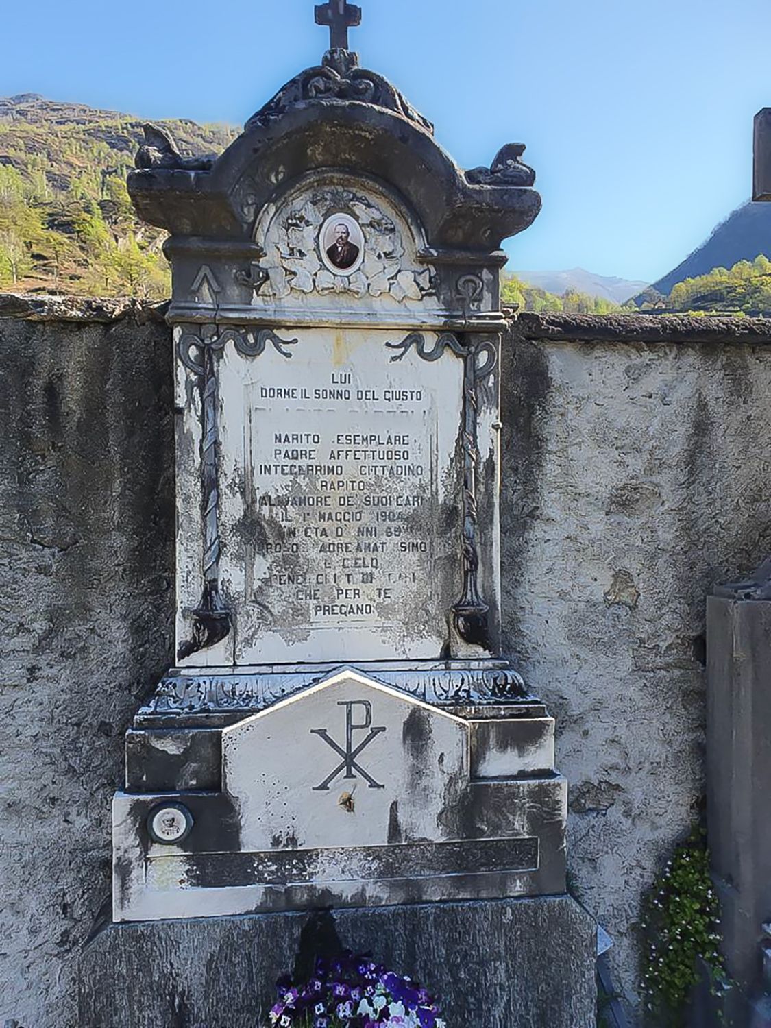 Una lapide con sopra una croce in un cimitero.