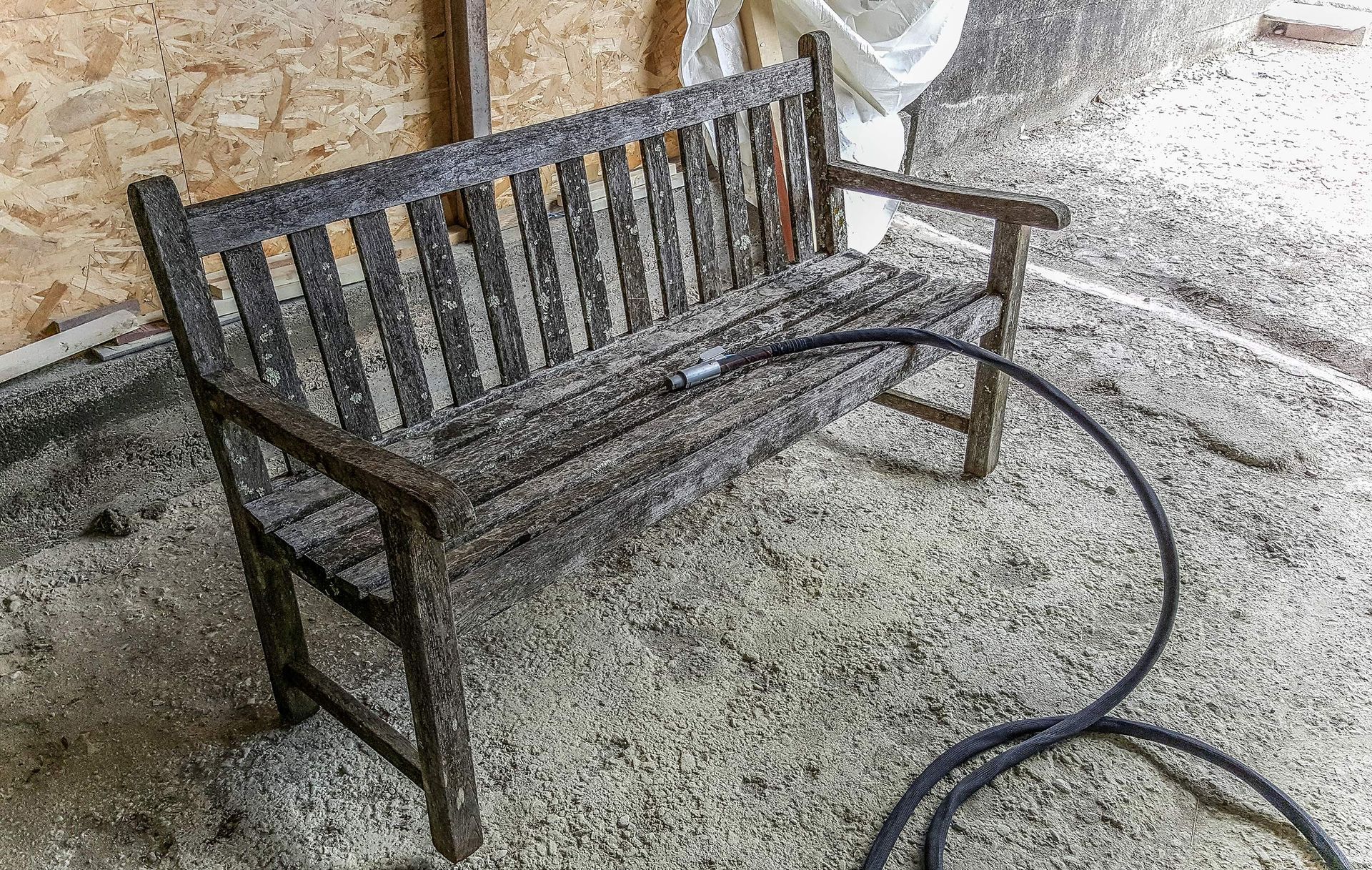A terra, accanto a un tubo, è appoggiata una panca di legno.