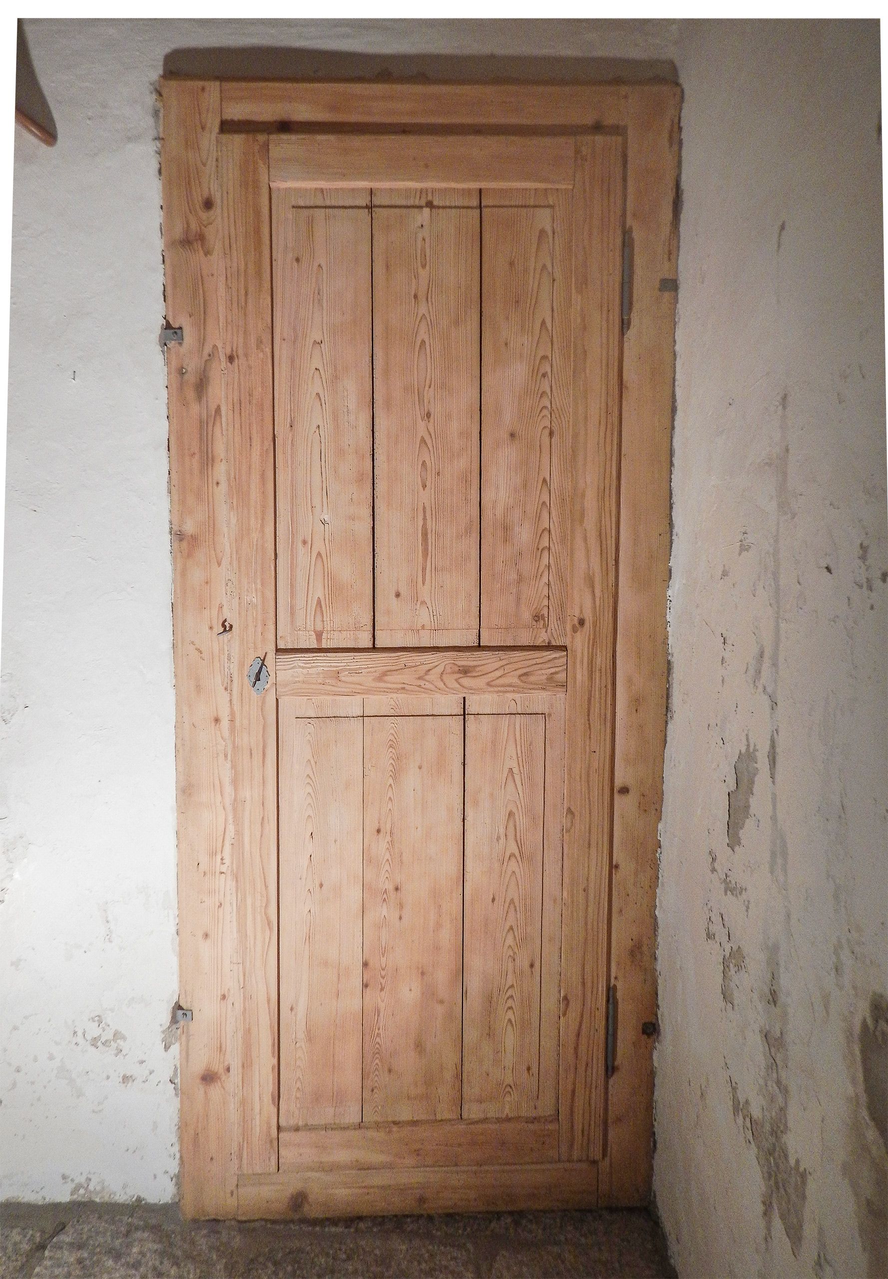 Una porta di legno è contro un muro bianco