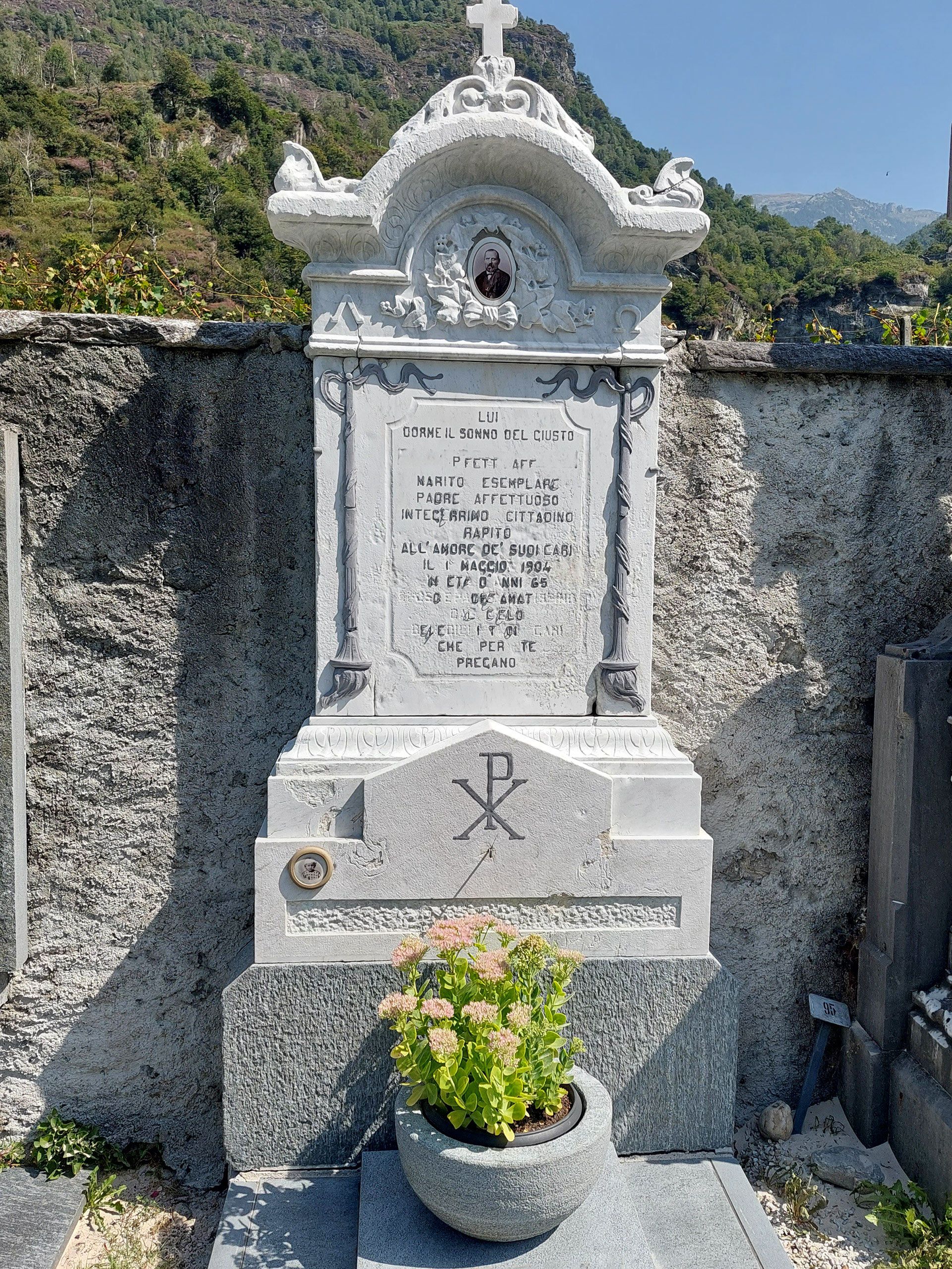 Una tomba con sopra un vaso di fiori in un cimitero.