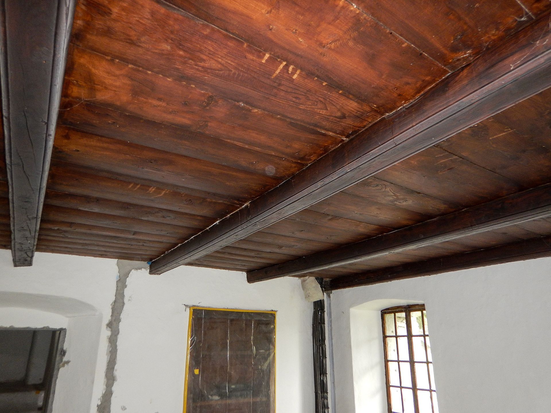 Una stanza con il soffitto in legno e una finestra