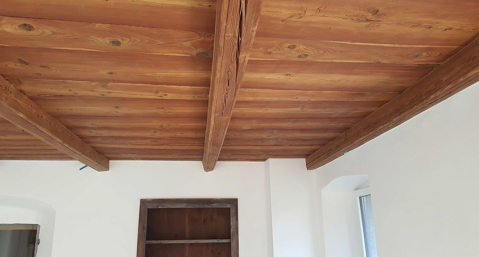 Una stanza con il soffitto in legno e le pareti bianche.