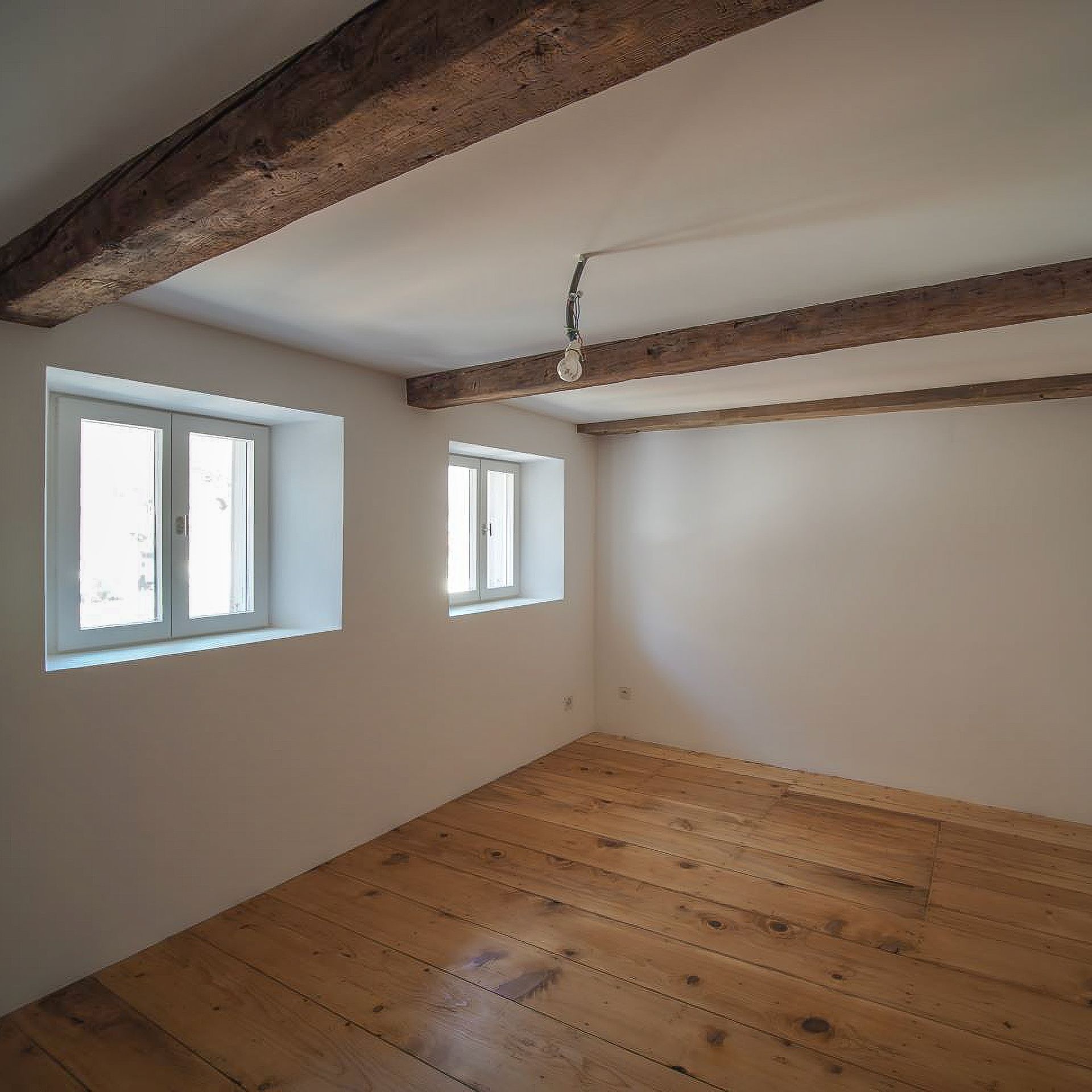 Una stanza vuota con pavimenti in legno e pareti bianche