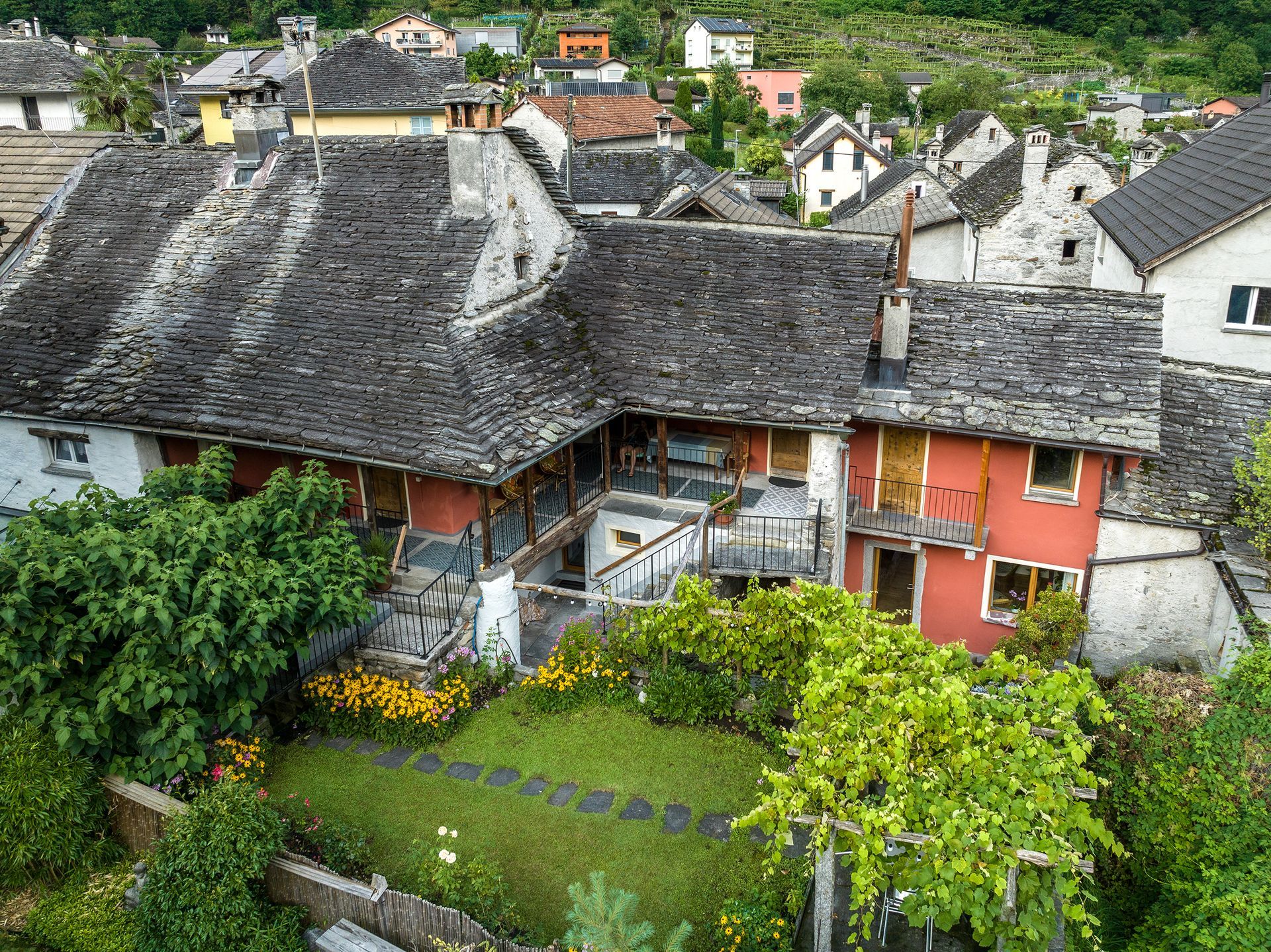 Una veduta aerea di una casa con tetto in piode e giardino.