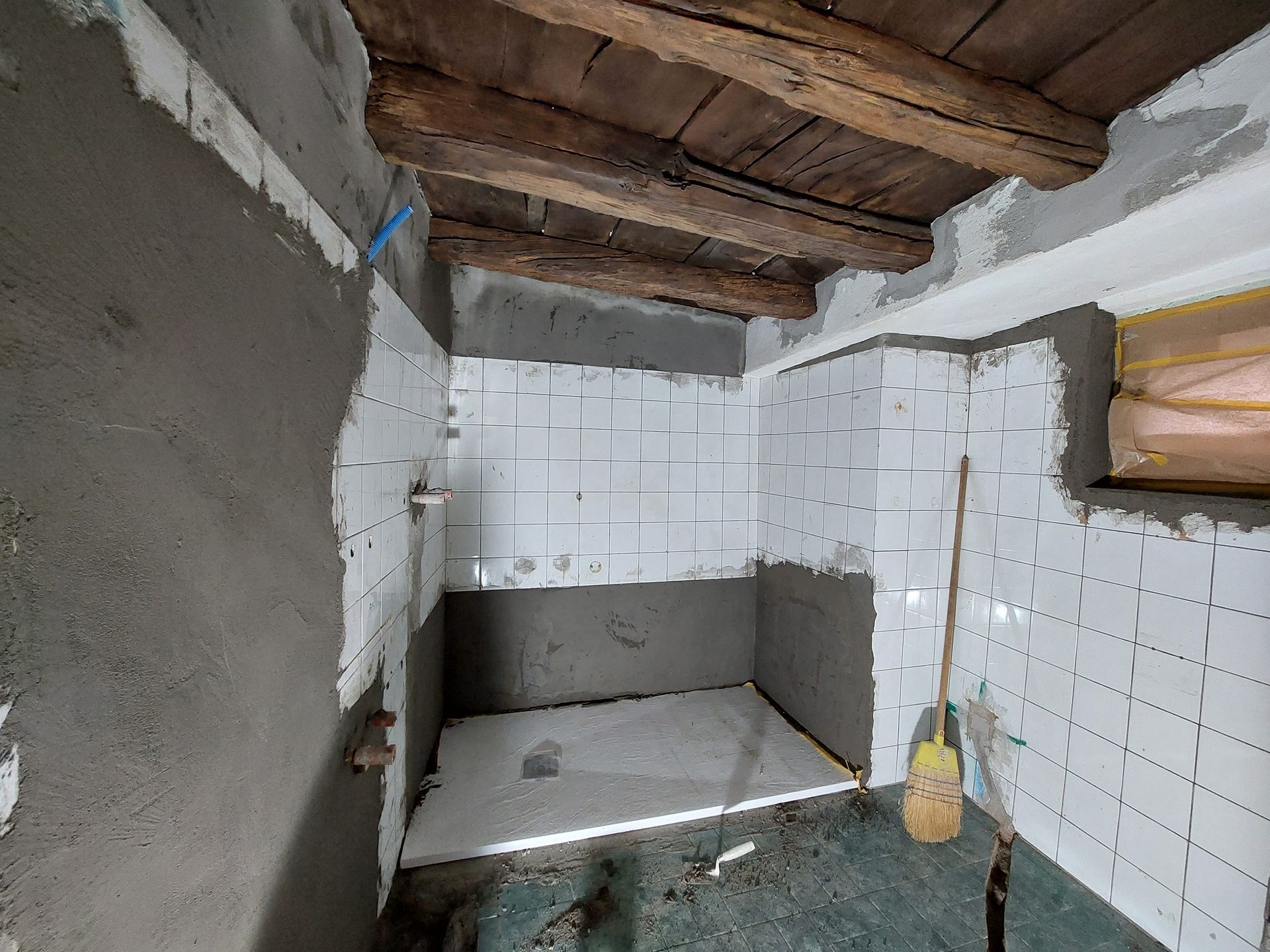 Un bagno in costruzione con piastrelle bianche e travi in ​​legno.