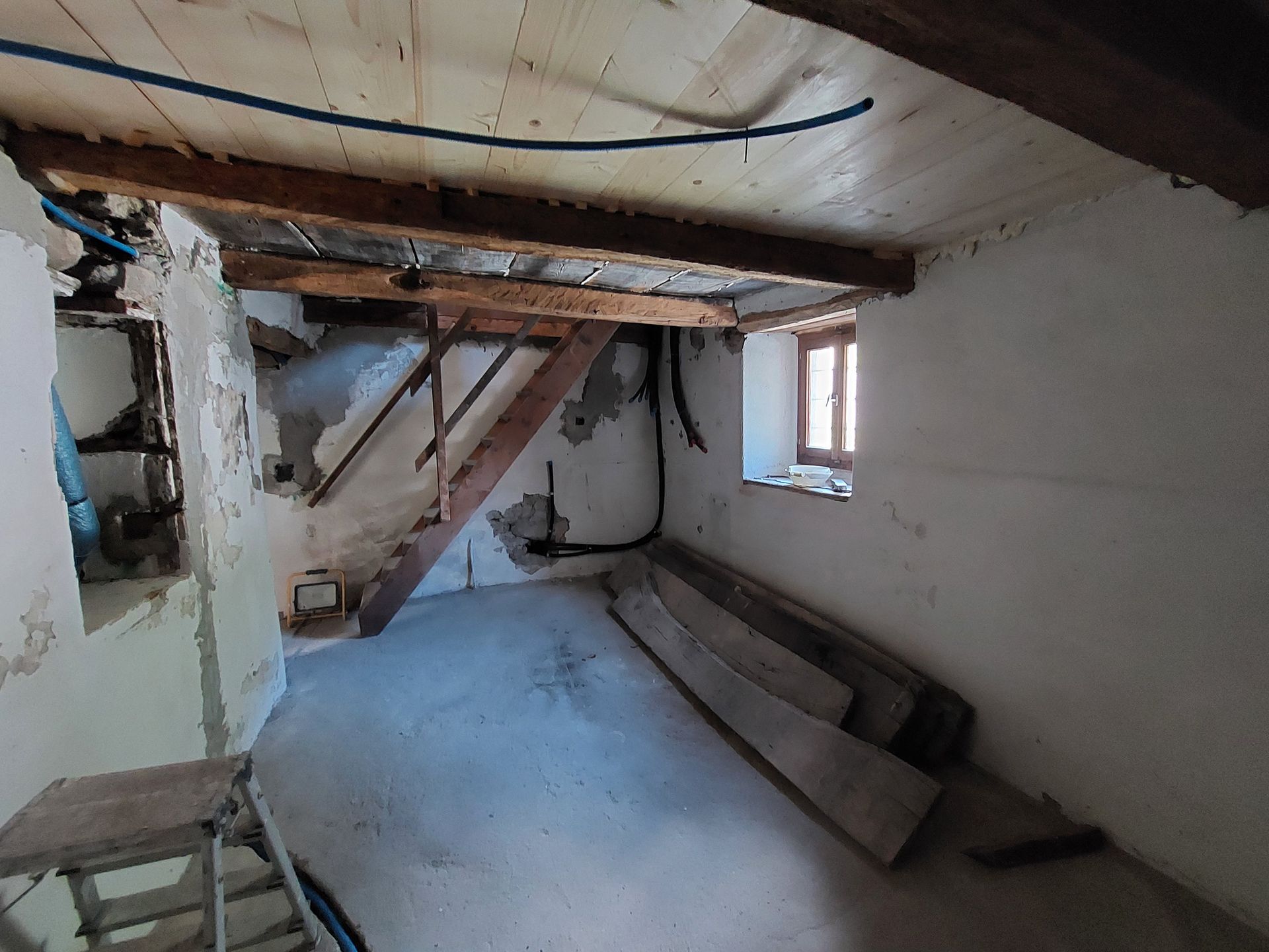Una stanza in ristrutturazione con il soffitto in legno e una finestra