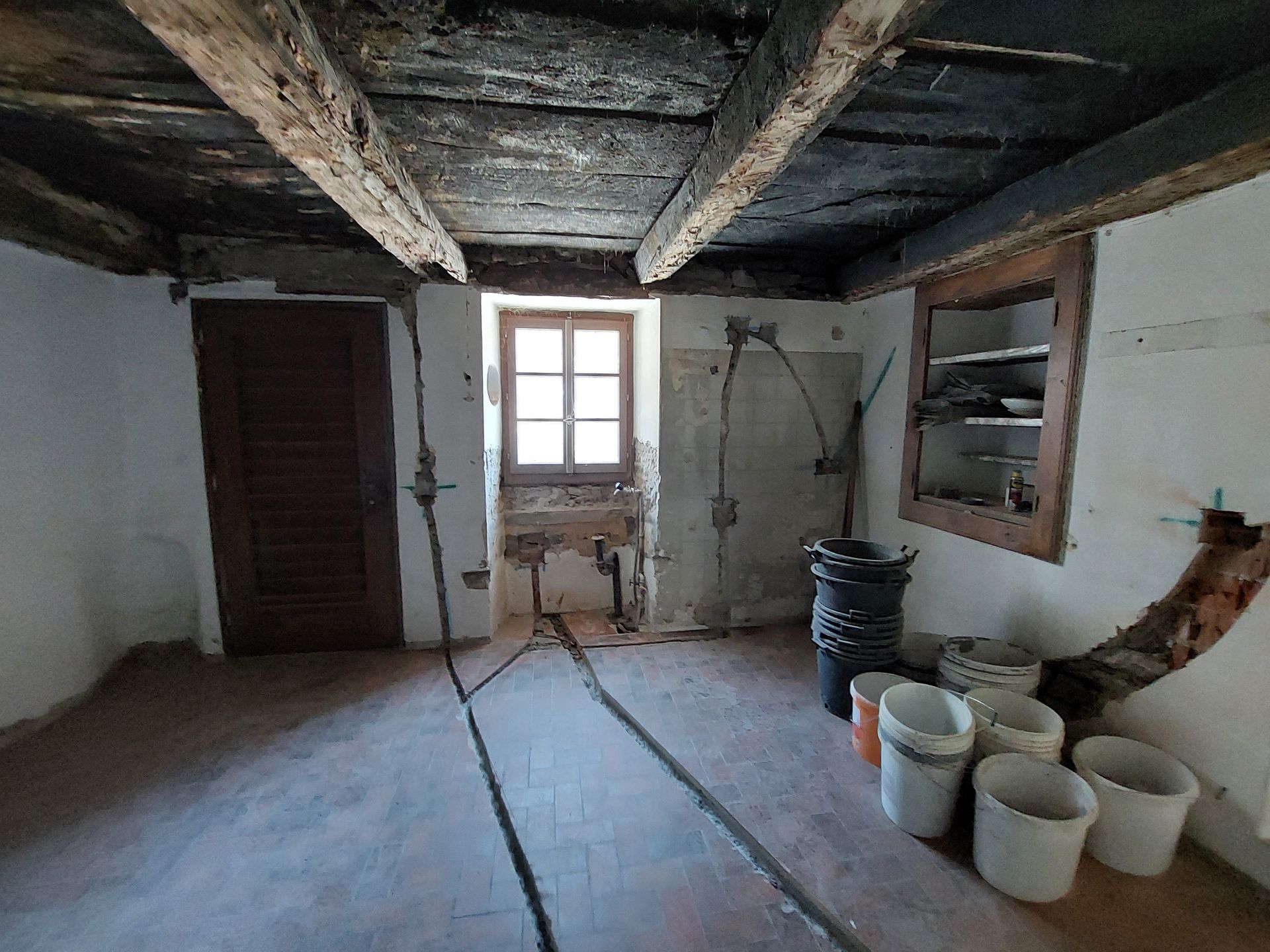 Una stanza con travi di legno e secchi sul pavimento